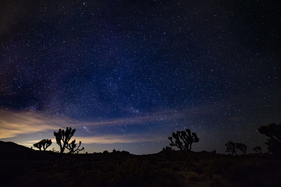 An Airstream trailer parked in the desert at night under a star-filled sky